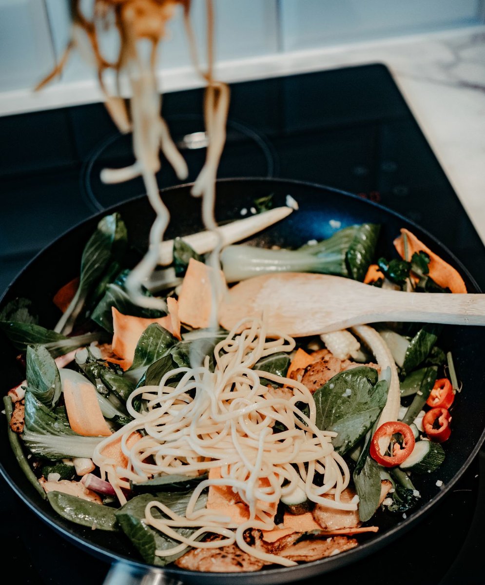 Mi bersama sayur sedang digoreng di dalam kuali di atas dapur